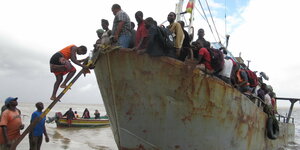 Menschen steigen von einem verrosteten Boot an Land