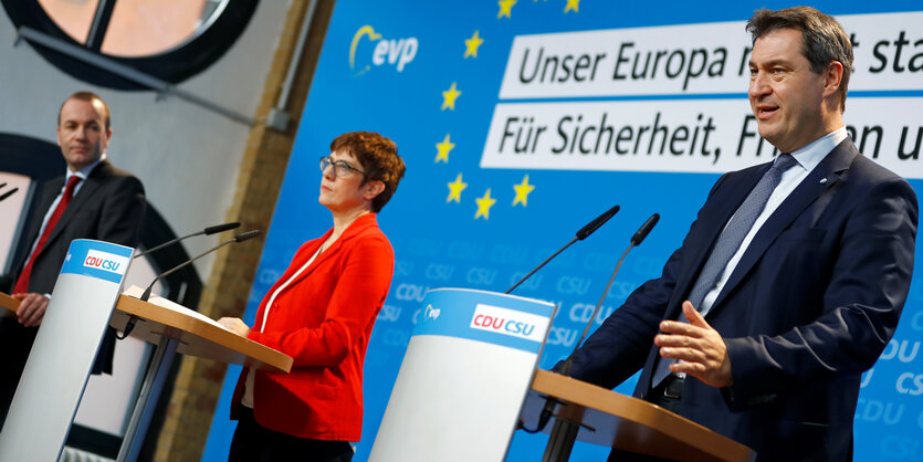 Manfred Weber, Annegret Kramp-Karrenbauer, Markus Söder stehen auf einem Podium. Die Aufnahme ist nach rechts gekippt