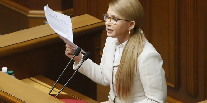 Frau mit langen blonden Haaren und Blättern in der Hand