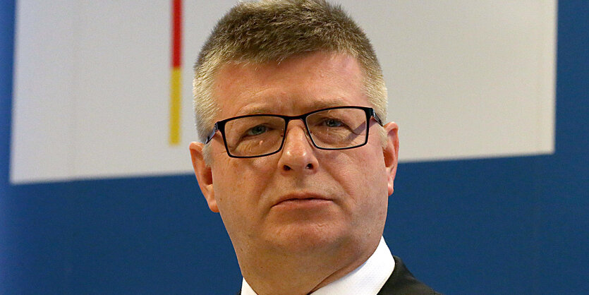 Gesicht von Thomas Haldenwang, Präsident des Bundesamts für Verfassungsschutz, vor Wand mit Schriftzug "Bundesamt für Verfassungsschutz"