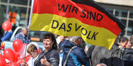 Eine Frau trägt eine Deutschland-Flagge mit der Aufschrift „Wir sind das Volk“