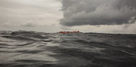 Menschen mit Rettungswesten sitzen in einem Boot auf dem Meer