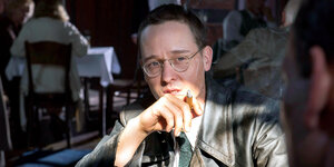 Ein Mann mit Brille raucht Zigarre
