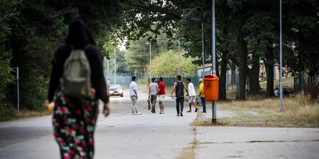 Bewohner einer Erstaufnahmeeinrichtung für Asylsuchende laufen auf der Straße