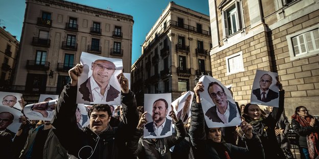 Demonstranten halten Plakate mit Gesichtern von katalanischen Seperatistenführern nach oben