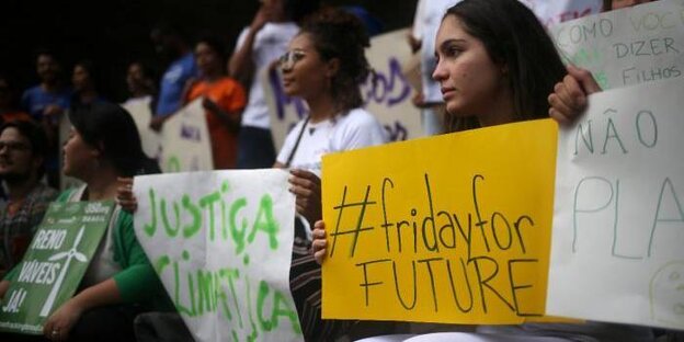 Junge Frauen halten Schilder, auf denen Parolen und "FridaysforFuture" steht