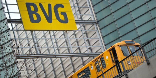 Eine U-Bahn fährt untern einem Schild her auf dem BVG steht