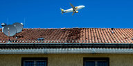 Ein Flugzeug fliegt über einem Gebäudekomplex, der der Unterbringung von Asylbewerbern in Abschiebungshaft dient.