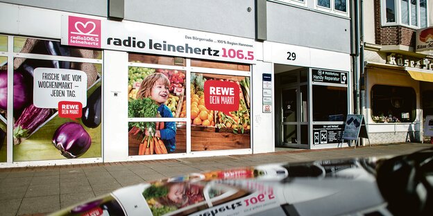 Ein Schild mit dem Logo des Radiosenders „Radio Leinehertz 106.5“ hängt an einem Bürogebäude.