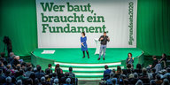 Baerbock und Habeck auf einer Bühne, im Hintergrund der Spruch: "Wer baut, braucht ein Fundament"