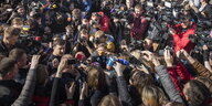 ein Mann umgeben von einer Menschenmenge und vielen Journalisten