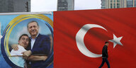 Mann vor türkischer Flagge und Wahlplakat