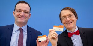 Jens Spahn und Karl Lauterbach halten Organspendeausweise hoch.