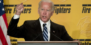 Der ehemalige US-Vizepräsident Joe Biden steht an einem Redepult und hält den Zeigefinder hoch.