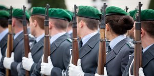 Soldaten und Soldatinnen vom Wachbataillon der Bundeswehr stehen nebeneinander mit Gewehren in der Hand.