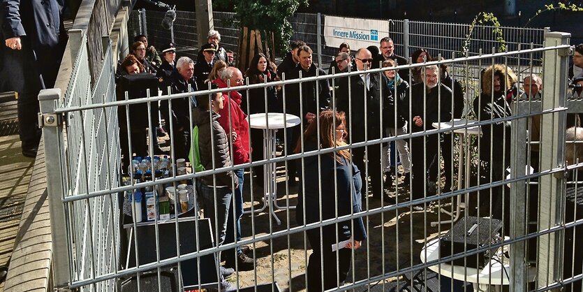 Menschen stehen in einem eingezäunten Bereich in der Nähe des Bremer Hauptbahnhofs.