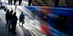 Menschen auf dem Bahnsteig, gerade fährt ein Zug ein