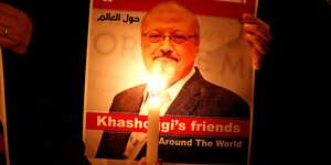Plakat, das den ermoderten Journalisten Khrashoggi abbildet vor einer brennenden Kerze