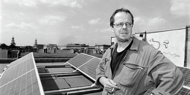 Andreas Baier steht auf einem Dach und raucht eine Zigarette