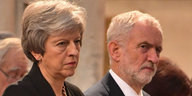Theresa May sitzt neben Jeremy Corbyn, beide schauen skeptisch