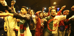 Menschen mit Algerienfahnen stehen eng zusammen und jubeln