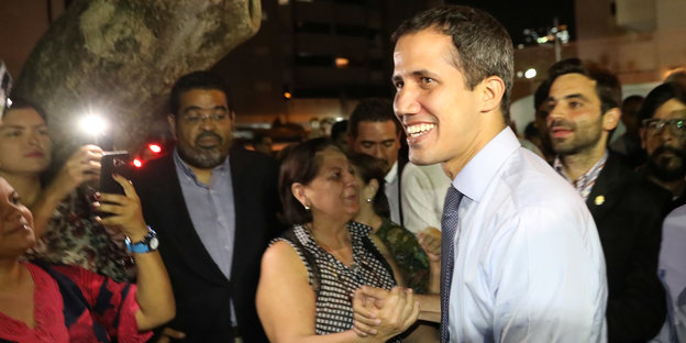 Juan Guaidó begrüßt eine Frau und wird von umstehenden Menschen angelächelt