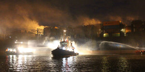 Löschboote löschen nachts einen Brand auf einem Containerschiff.