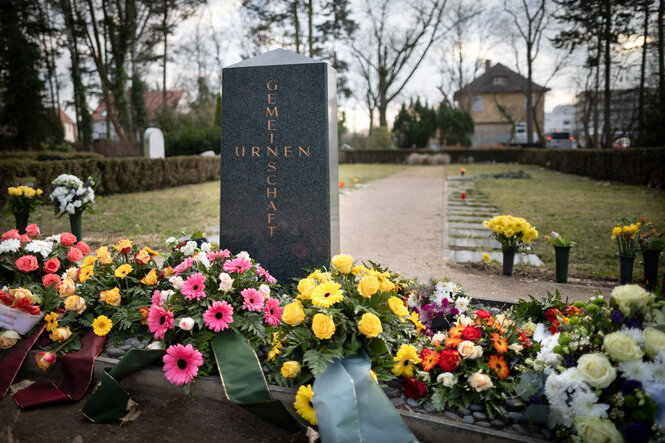 Blumen liegen vor einem Grabstein