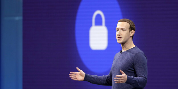 Ein Mann, mark Zuckerberg, vor einem blau-weißen Symbol