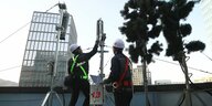 Arbeiter montieren getarnte 5G-Antennten auf einem Hausdach in Seoul.