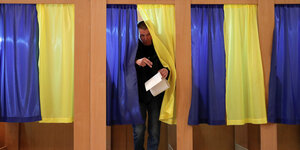 Wähler verlässt Kabine, Vorhänge sind Gelb und Blau