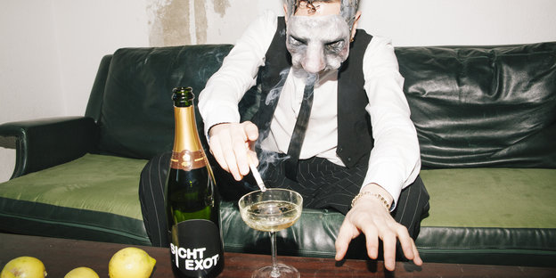 Ein Mann mit einer Hasenmaske ascht in ein Champagnerglas