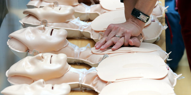 Hände liegen auf nachgebildeten Oberkörpern und demonstrieren eine Herzdruckmassage für den Notfall