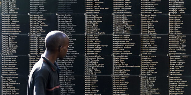 Ein Mann steht vor dem Mahnmal, das an den Völkermord erinnert, darauf sind etliche Namen aufgelistet.