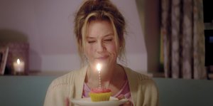Eine Frau schaut auf einen Cupcake mit einer kleinen Kerze darauf