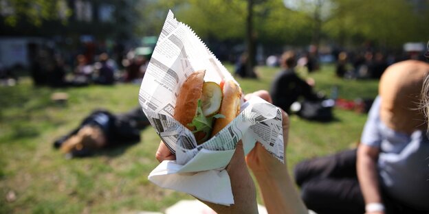 Eine Hand hält einen Hamburger Eine Hand hält einen Hamburger