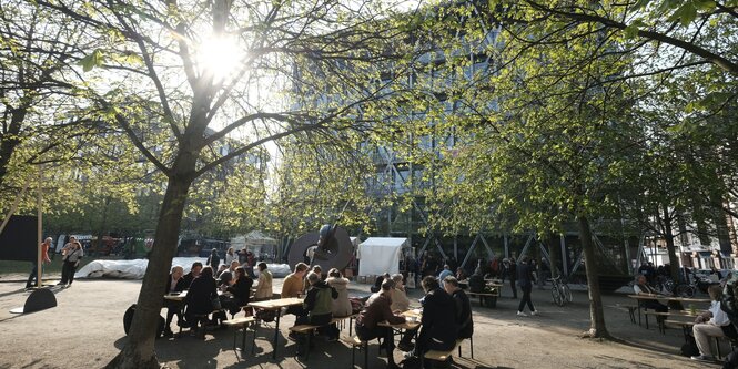 Menschen sitzen vor dem taz Neubau