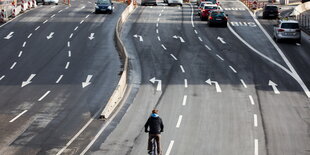 ein Radfahrer auf der linken Spur einer dreispurigen Straße