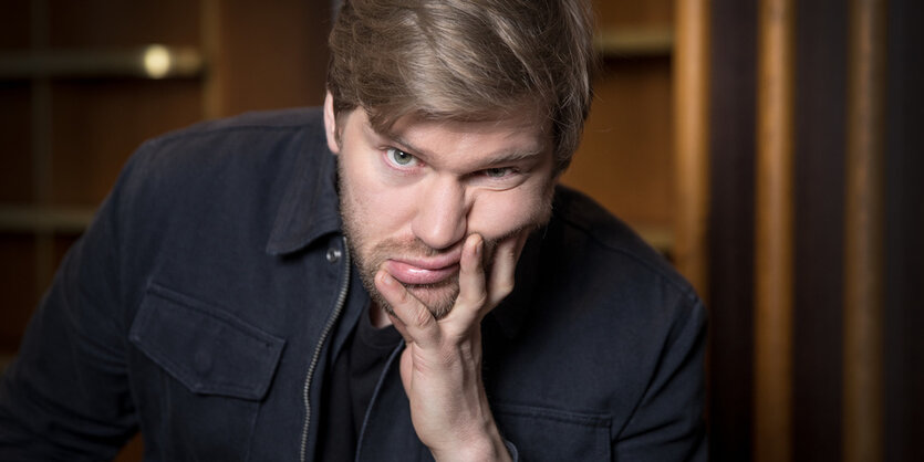 Satiriker Shahak Shapira stützt sich auf seine Hand und guckt zerknautscht