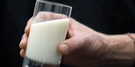 Eine Hand hält ein Glas Milch
