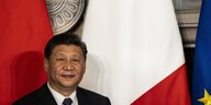 Xi Jinping steht vor den Flaggen Chinas, Italiens und der EU