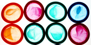 Acht bunte Kondome liegen nebeneinander