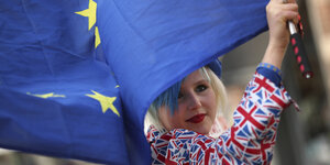 Eine Frau in den britischen Farben gekleidet schwenkt eine Europafahne