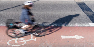 Eine Person fährt auf einem Radstreifen Fahrrad und trägt dabei Helm