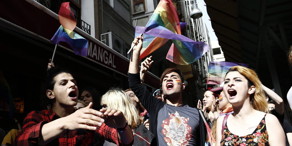 Personen schreien und tragen Regenbogenfahnen