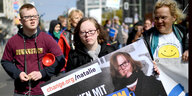 Zwei junge Menschen mit Downsyndrom halten ein Plakat auf einer Demo