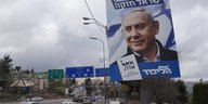 Auf einer Straße hängt ein Wahlplakat mit hebräischer Sprache und dem Gesicht von Benjamin Netanjahu