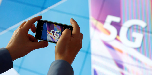 Jemand fotografiert mit einem Smartphone einen Bildschirm, auf dem 5G steht