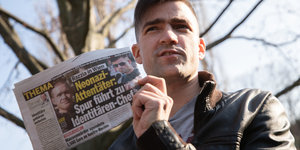 Ein Mann hält eine Boulevardzeitung in der Hand