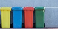 Vier farbige Müllonnen stehen nebeneinander.